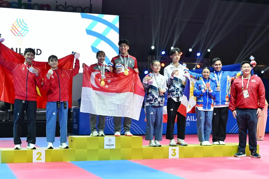 许鸿杰和戴雅娜手持新加坡国旗登上最高领奖台，颁奖嘉宾是新加坡全国奥理会秘书长蔡荣俊（右一红衣）。（每日新闻）