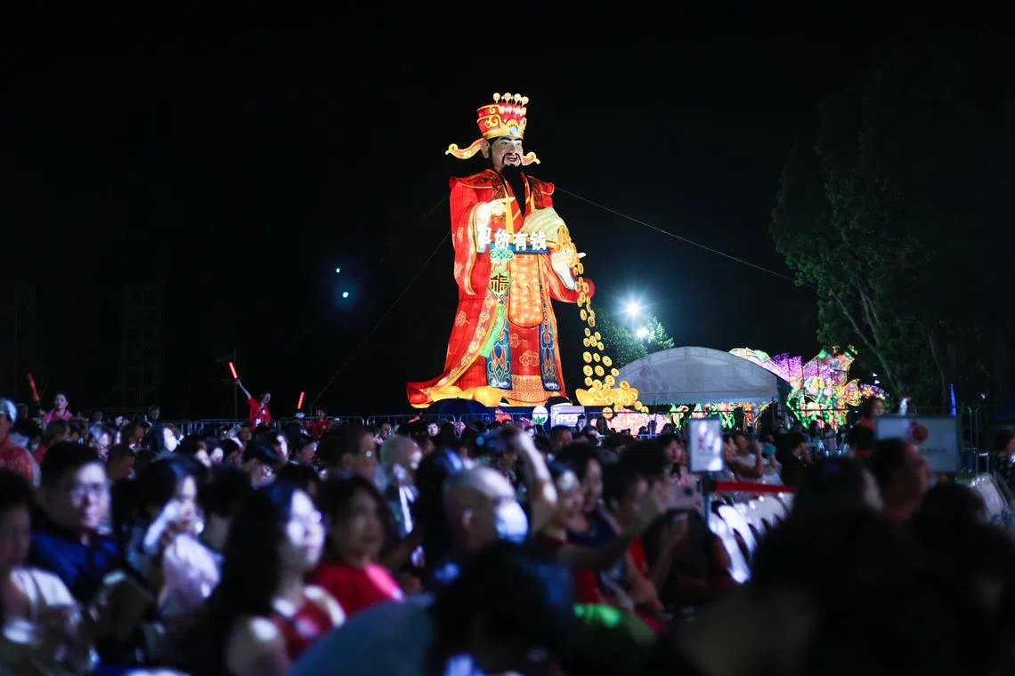 除了舞台上的歌舞演出，滨海湾花园四处布置了多个大型灯饰。靠近舞台的18米高财神爷灯饰尤其受欢迎，大家都想沾沾财神爷的喜气，在新一年里财源滚滚、好运连连。（张俊杰摄）