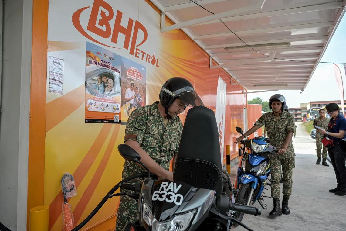 两名军人星期六（9月27日）在吉隆坡地区的一家油站，顺利用大马卡验证身份的方式，以每公升1.99令吉（约0.61新元）的政府补贴价添购RON95汽油。（马新社）