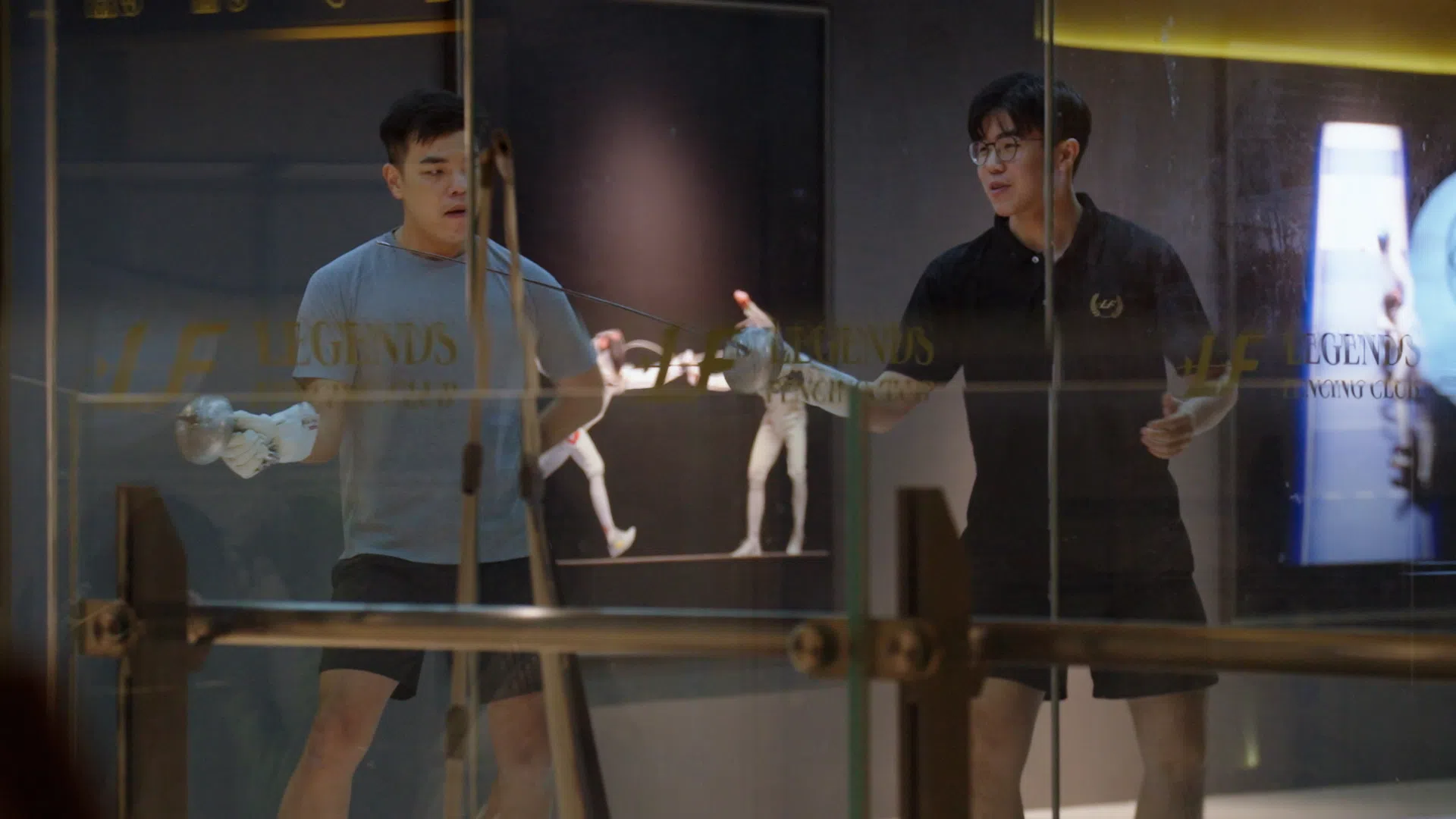 潘绪哲（右）为了筹集明年出国比赛的费用，在一家击剑俱乐部兼职当教练。（视频截图）