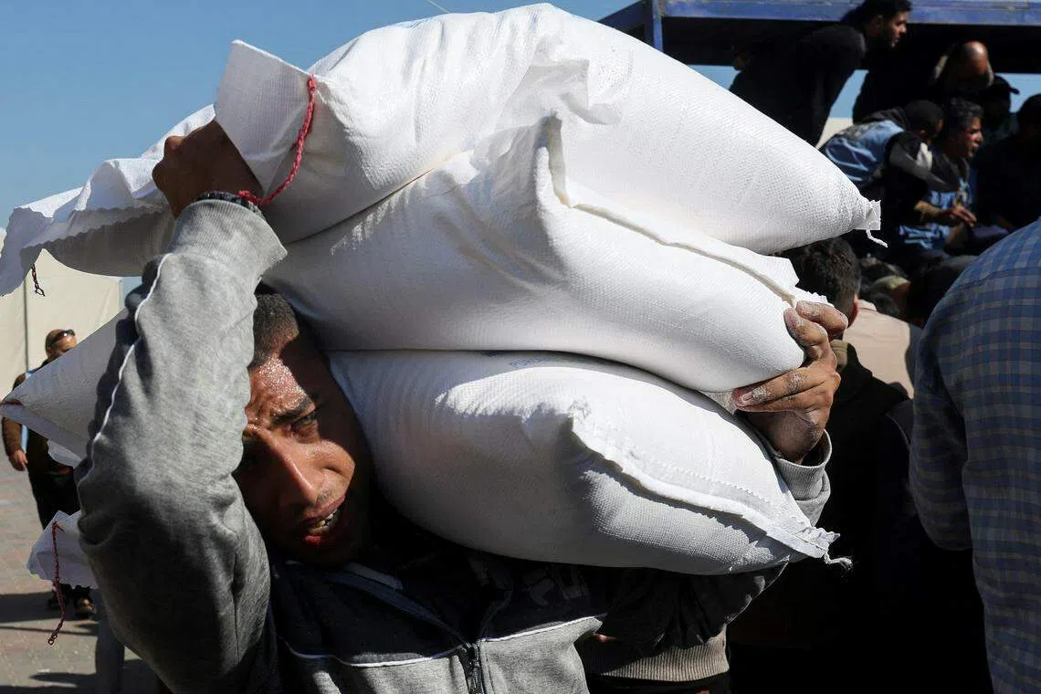 联合国近东巴勒斯坦难民救济和工程处（UNRWA）星期三在加沙南部城市汗尼尤斯发放救济品，图为一名巴勒斯坦男子在搬运面粉。（路透社）