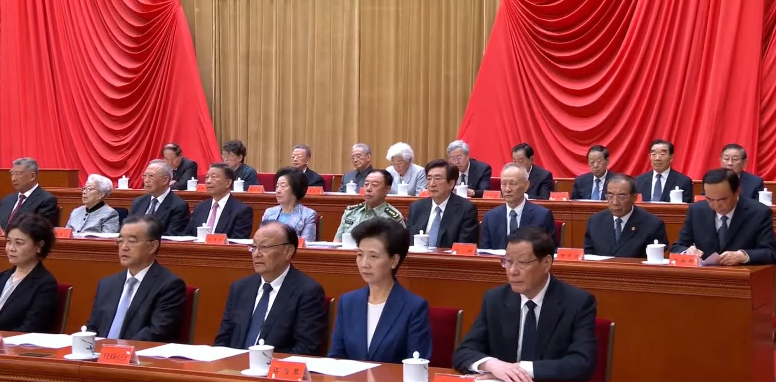 多名已退休的中共政治局前委员星期一（8月17日）上午在北京人民大会堂，出席纪念江泽民诞辰100周年大会，并在主席台就坐，包括中国前国家副主席李源潮（中间一排左四起）、国务院前副总理孙春兰、中央军委前副主席范长龙、北京市委前书记郭金龙、国务院前副总理刘鹤、中央纪律检查委员会前副书记杨晓渡、新疆维吾尔自治区前党委书记陈全国、中央政法委前书记郭声琨。（央视直播视频截图）