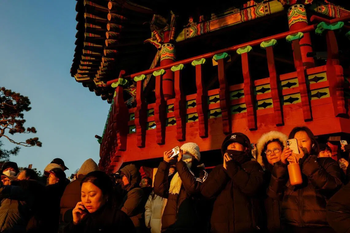 韩国民众在首尔的一座天文台迎2026年的第一缕阳光，一名女游客双手合十祈祷许愿。（路透社）