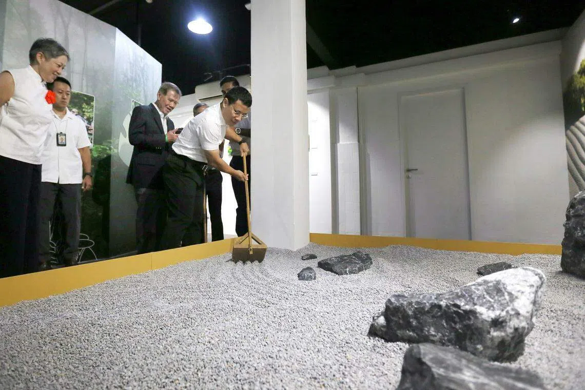 国家发展部长李智陞（右）在干燥花园中体验，该区域的设计旨在营造宁静祥和的空间，访客可以尝试耙碎石子的冥想练习，让思绪平静。（吴瑞恩摄）