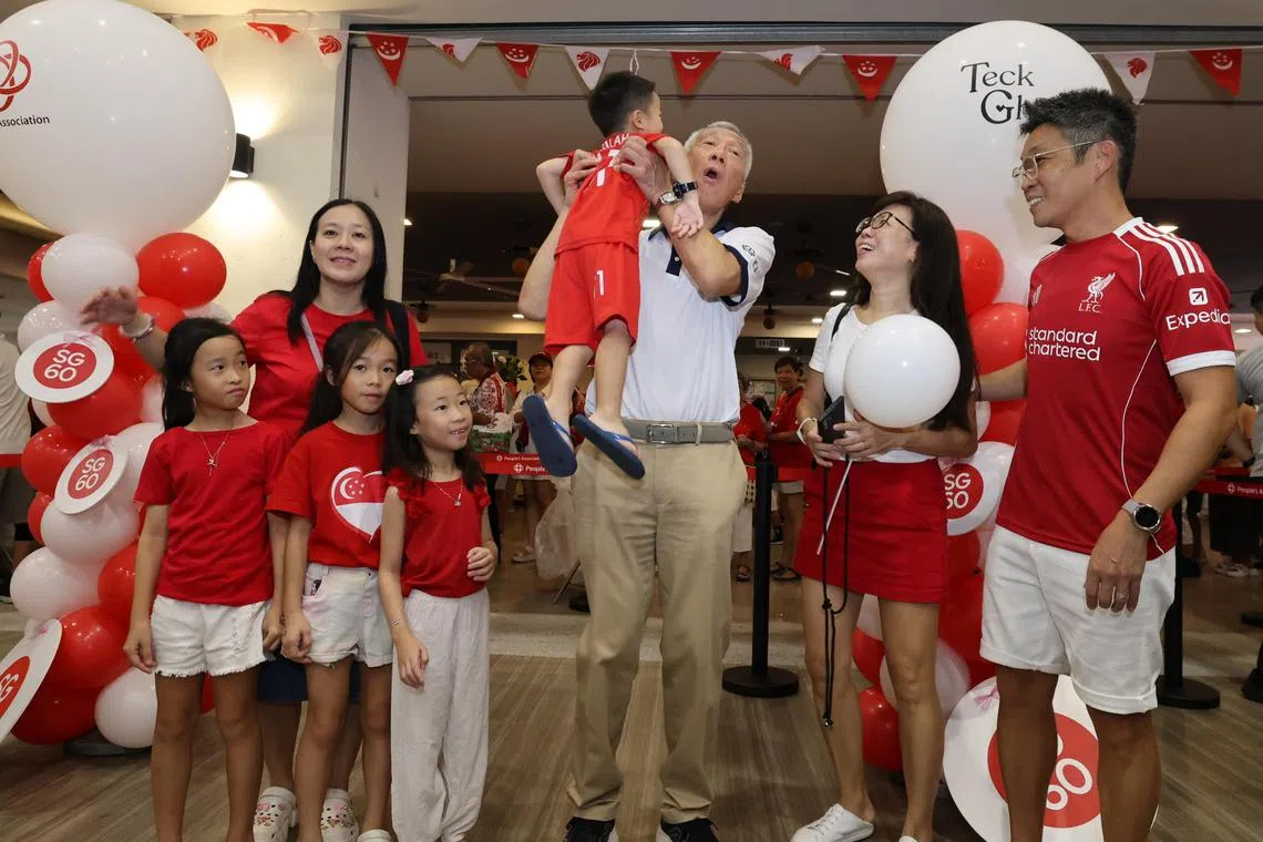 国务资政李显龙（白衣）在国庆日当天出席德义区国庆敬礼仪式，与居民亲切互动，对新加坡的未来主人翁呵护有加。（梁麒麟摄）