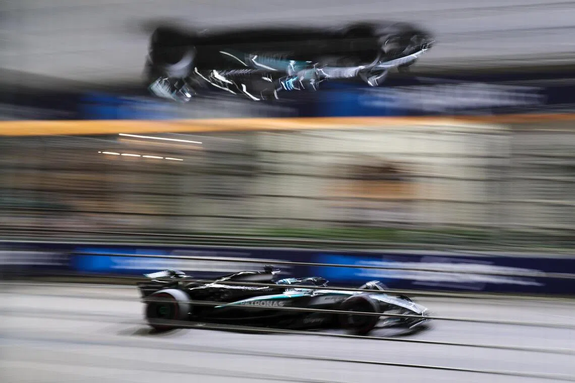 拉塞尔的赛车高速驶过赛道，经过摄影师的巧思，赛车倒映在路旁巴士站的金属屋顶上。（张俊杰摄）