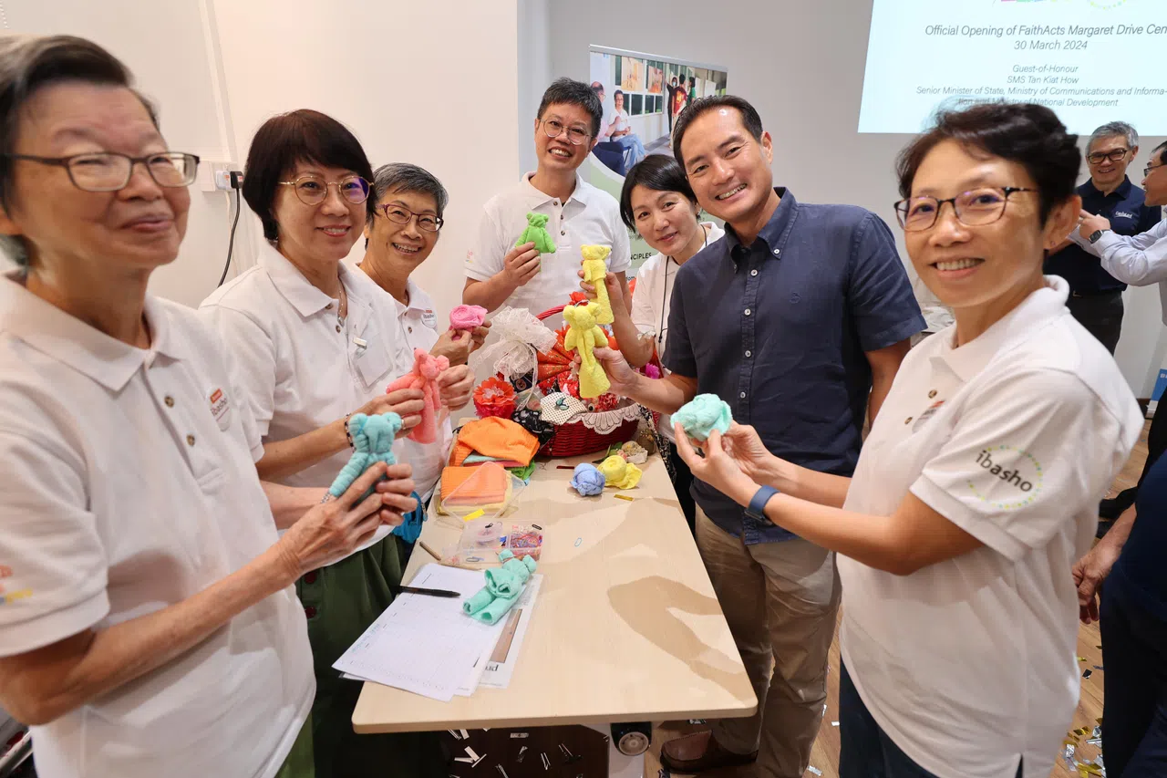 通讯及新闻部兼国家发展部高级政务部长陈杰豪（右二）在林金兰（左三）和朋友一同组织的手工艺课程展位上，拿着布料手工艺品合影。（梁麒麟摄）