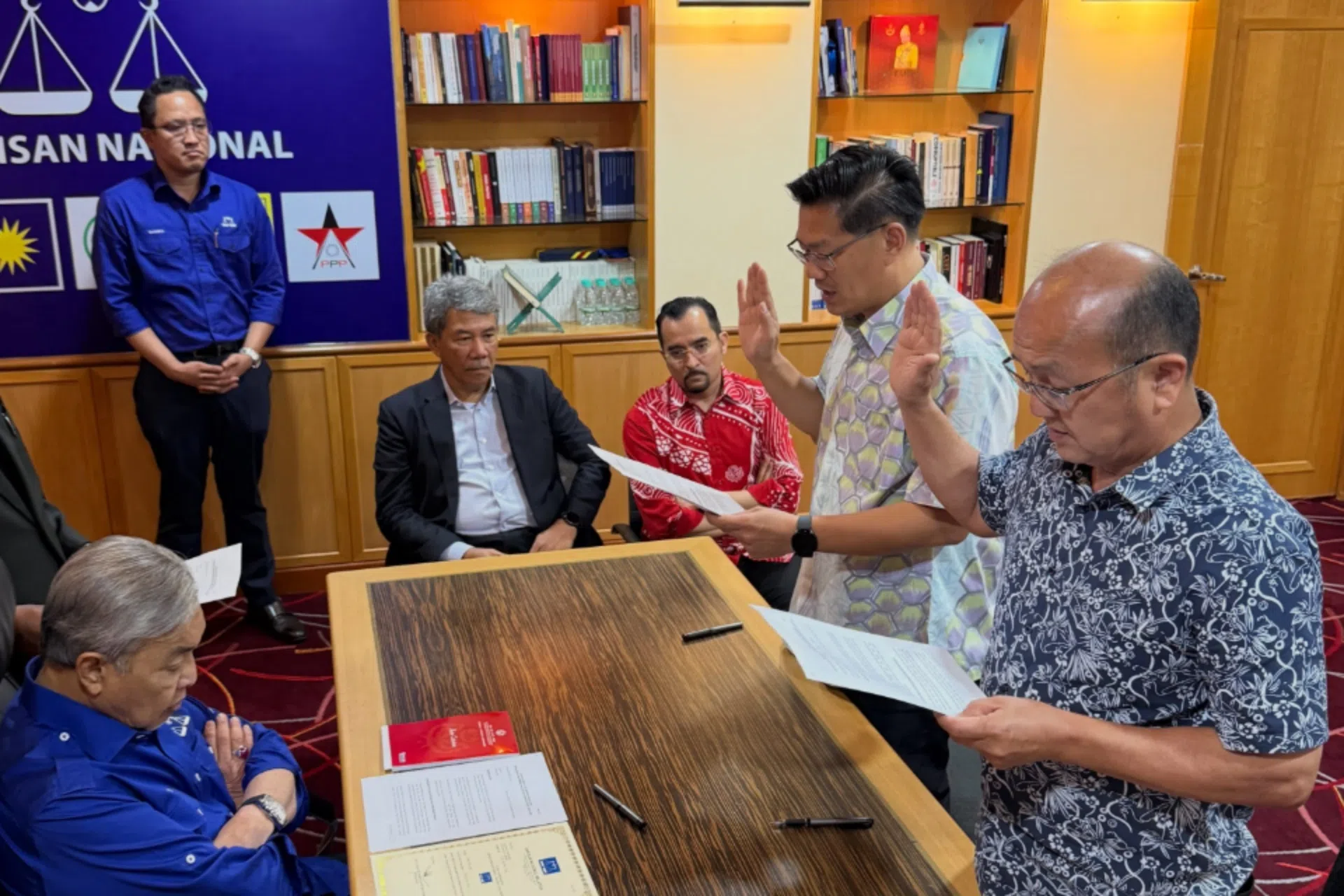 马华甲州马接再也区原任议员魏喜森（站者右）与吉里望区原任议员林万锋（站者左）星期三（10月28日），在巫统总部向国阵主席阿末扎希（左）领取候选人委任状，并宣誓效忠国阵。左三为国阵署理主席莫哈末哈山，左四为巫统总秘书阿斯拉夫。（取自巫统总秘书阿斯拉夫脸书）