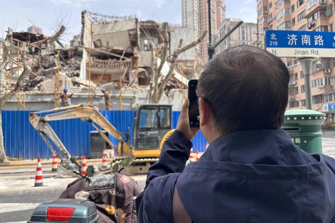 4月初受访当天，沈嘉禄带着记者走过儿时生活的街区。途经一处正在拆除的老建筑时，他拿出手机拍照。（黎康摄）