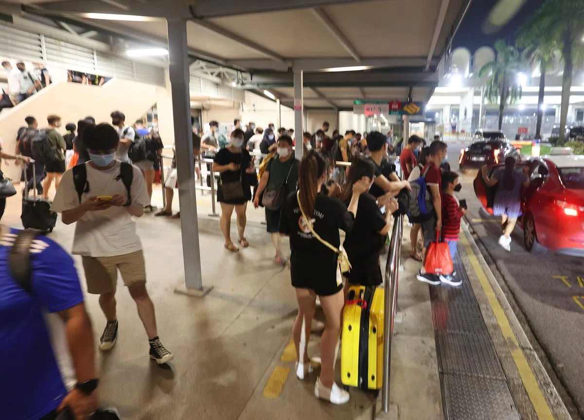 今晚，兀兰关卡外的巴士站和德士站也挤满了从新山回到新加坡的人。（邬福梁摄）