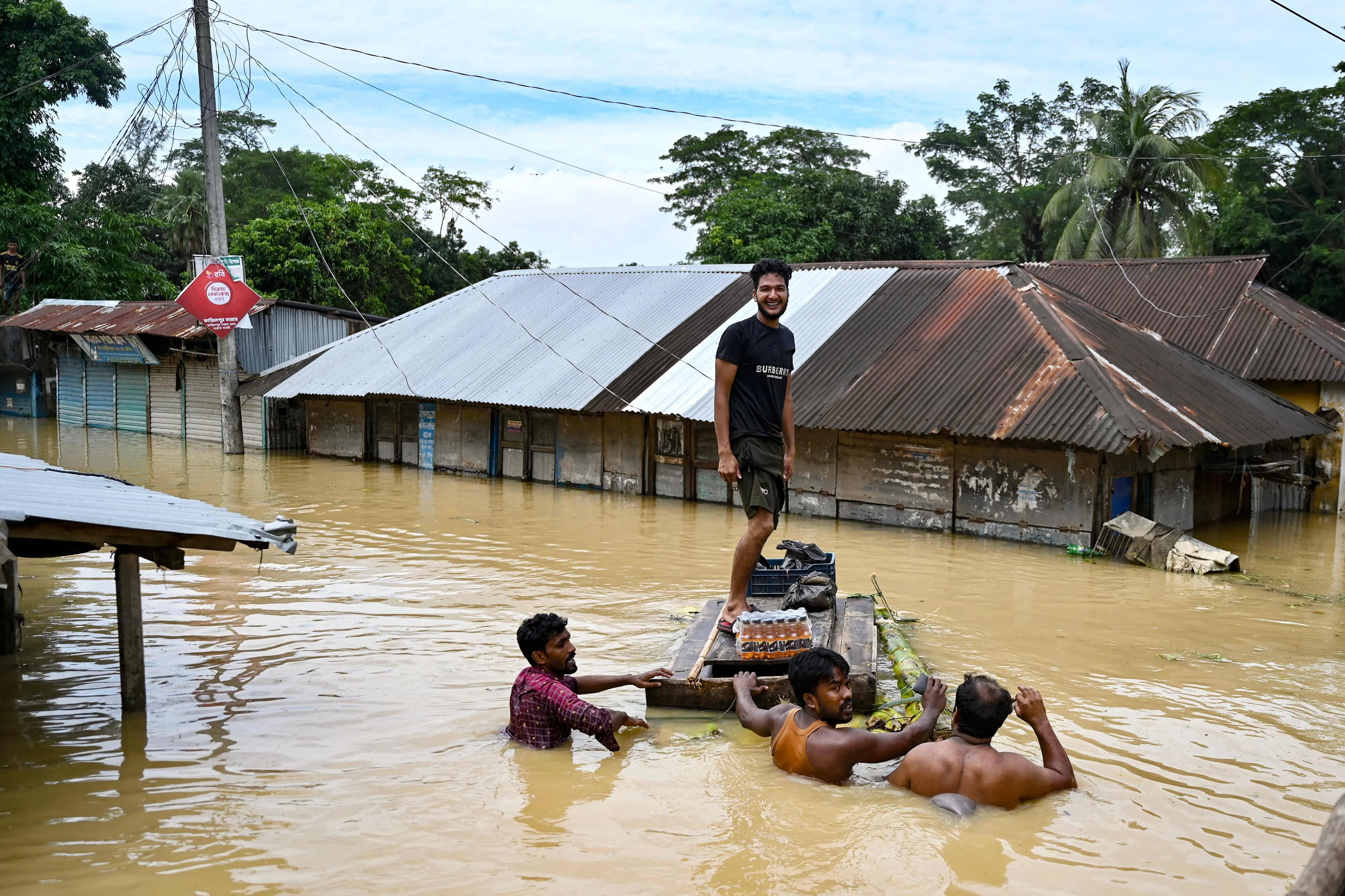 8月24日，几名灾民在孟加拉重灾区费尼已成水道的公路上涉水，前往安全地带。（法新社）