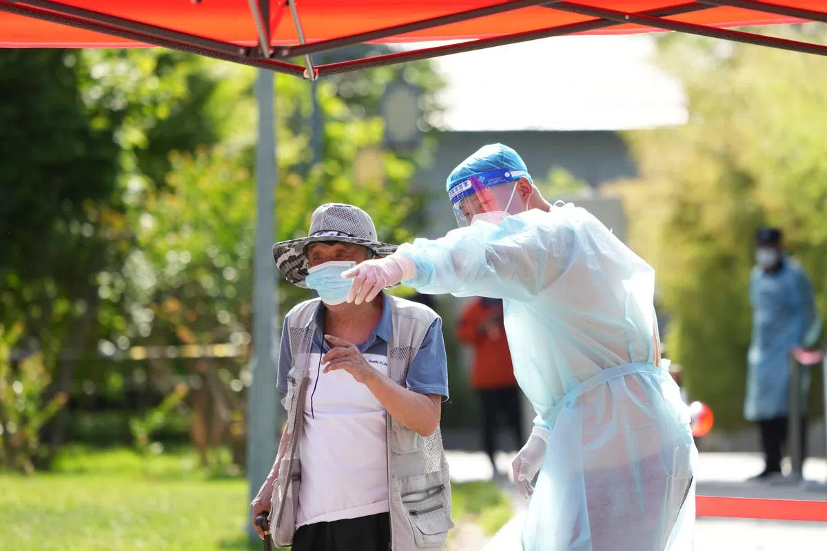 5月26日，在东城区建国门街道一处核酸采样点，志愿者（右）引导居民参加核酸检测。（新华社）