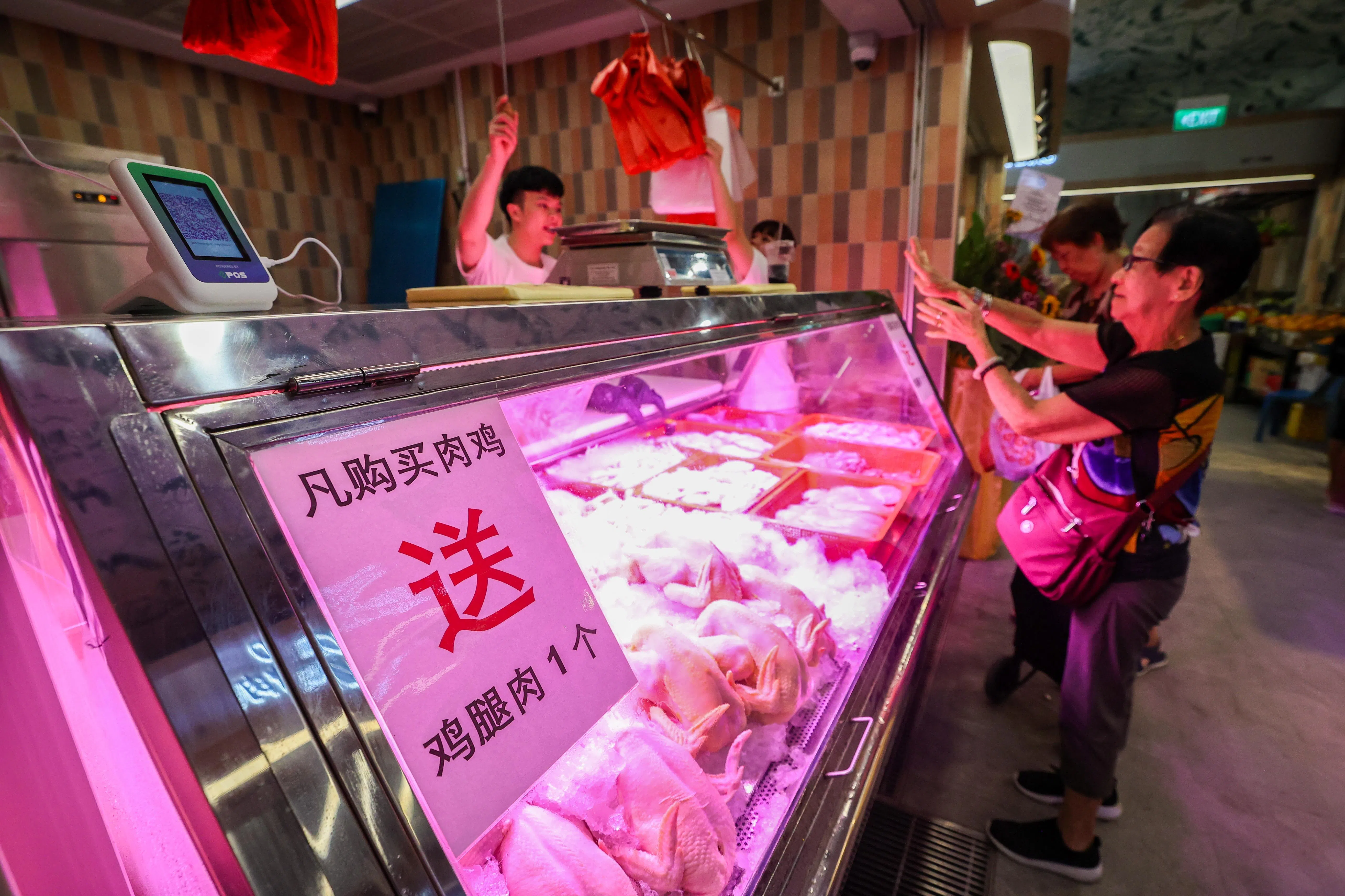 湿巴刹开张，鸡肉摊摊贩为吸引客人，星期二（1月27日）搞促销，消费者购买整只肉鸡，赠送一份鸡腿肉，每天促销不同。（陈斌勤摄）