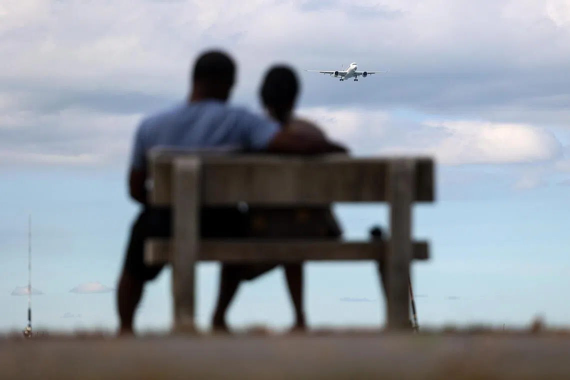 长椅上一对夫妻并肩而坐，看飞机缓缓飞过，享受安静流淌的时光。（关俊威摄）