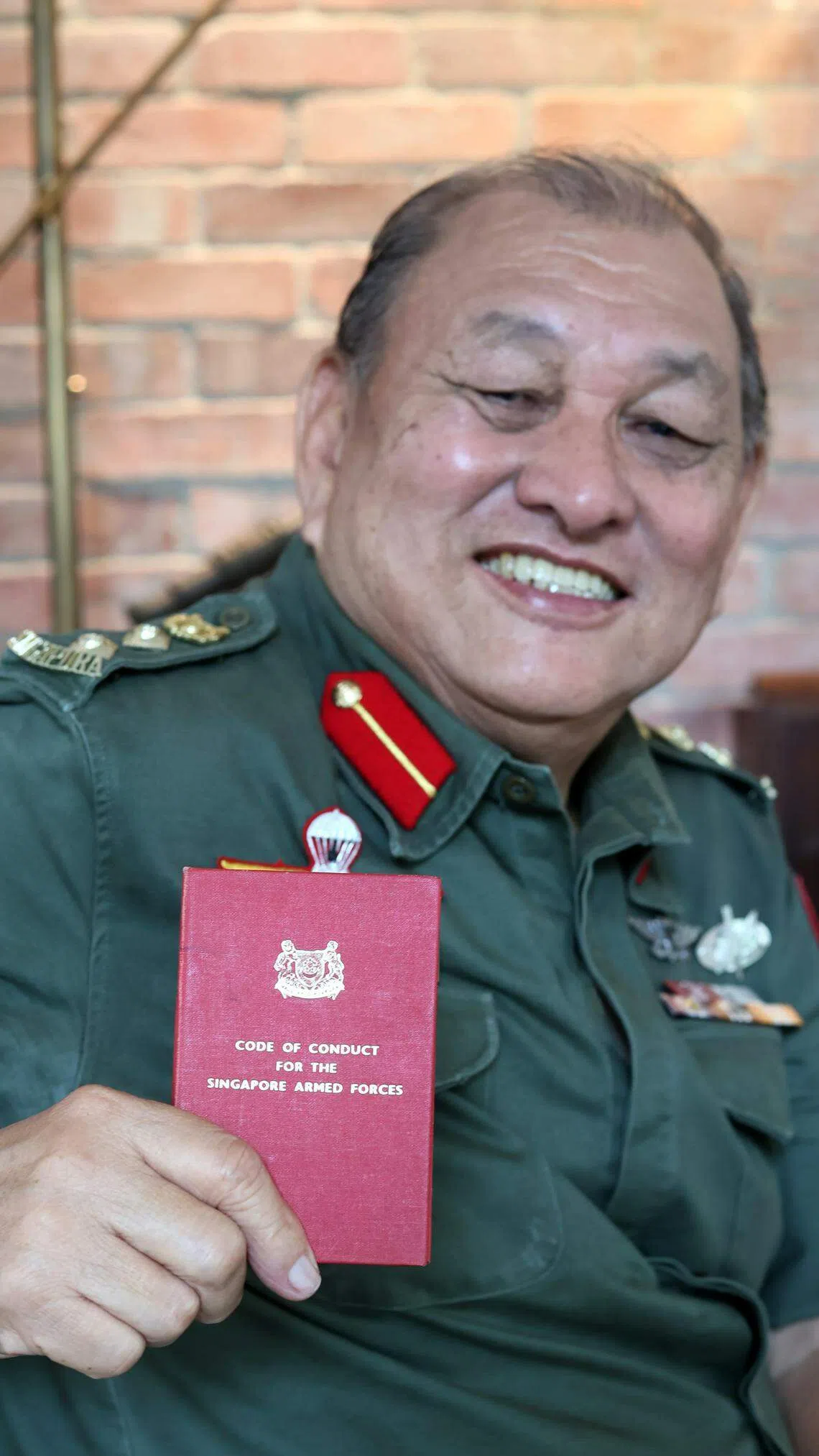 退休20多年，林耀平这本写着新加坡武装部队行为守则的小红册仍保留完整。（龙国雄摄）