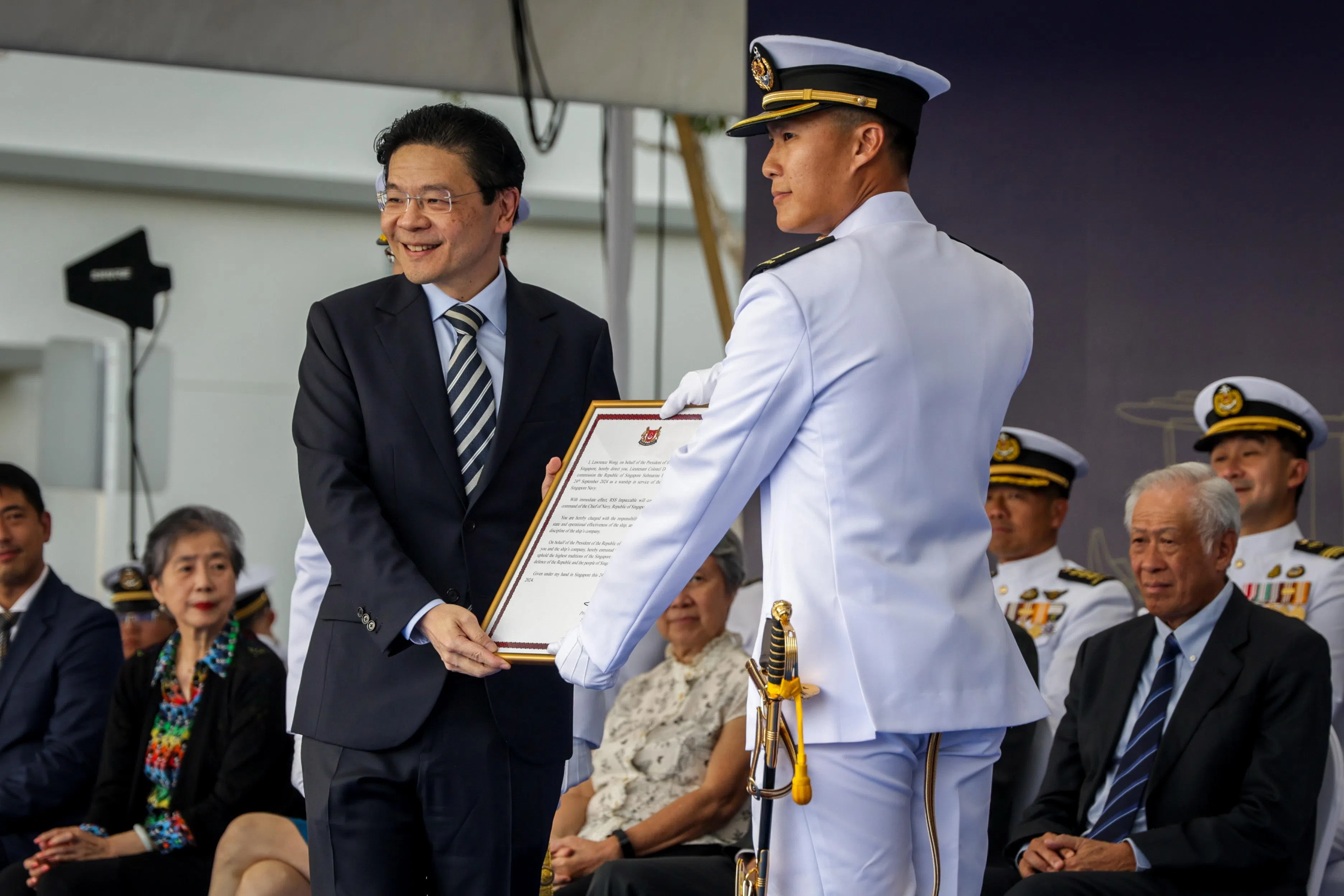 总理兼财政部长黄循财在两艘新潜艇的投役仪式上，将精锐号的投役委任状颁给指挥官曾伟胜中校。（叶振忠摄）