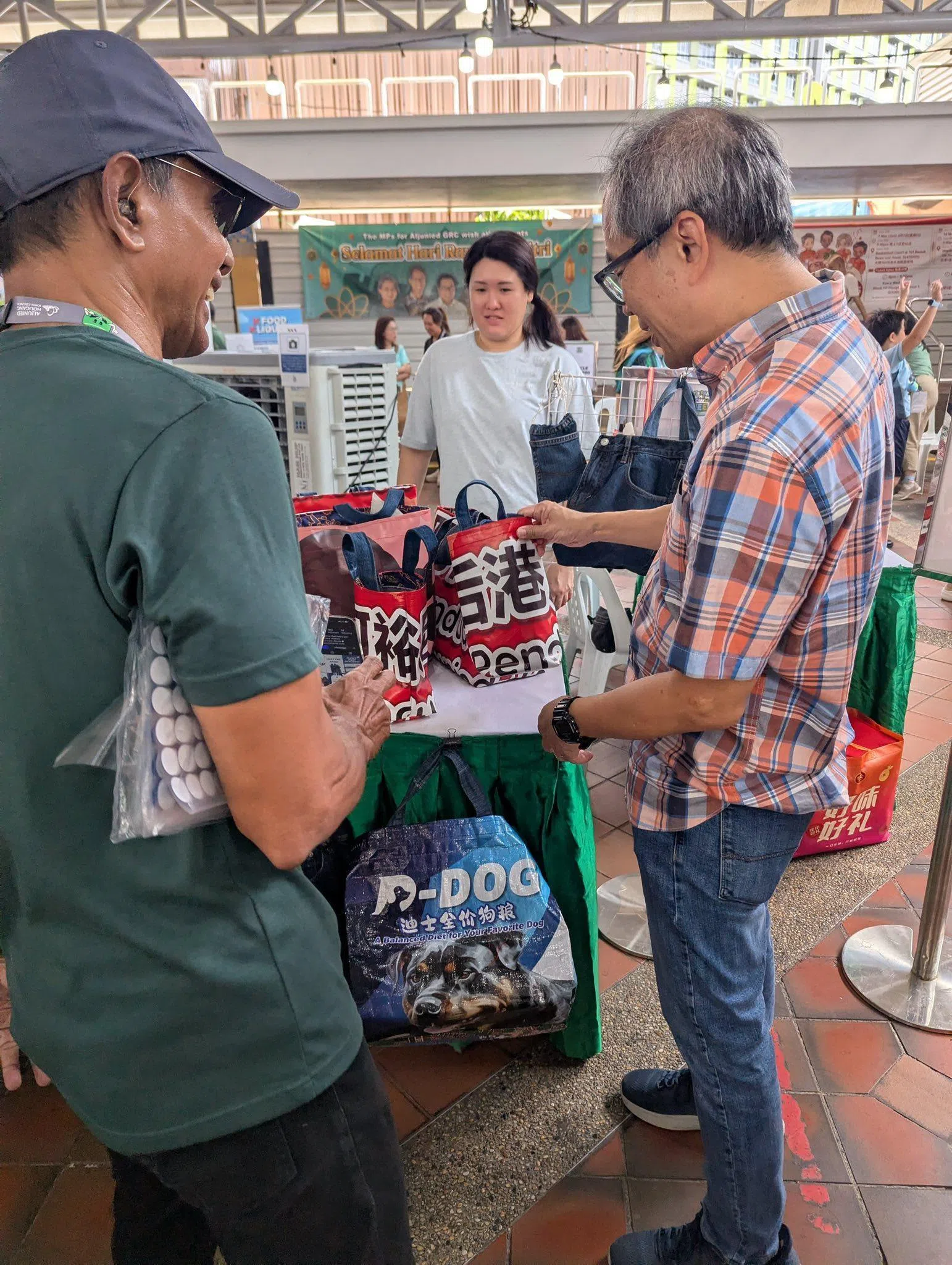 后港区议员陈立峰（右），在阿裕尼—后港市镇理事会“让市镇绿起来”环保展览上，欣赏居民陆女士用节日横幅改制的环保袋。（取自陈立峰脸书）