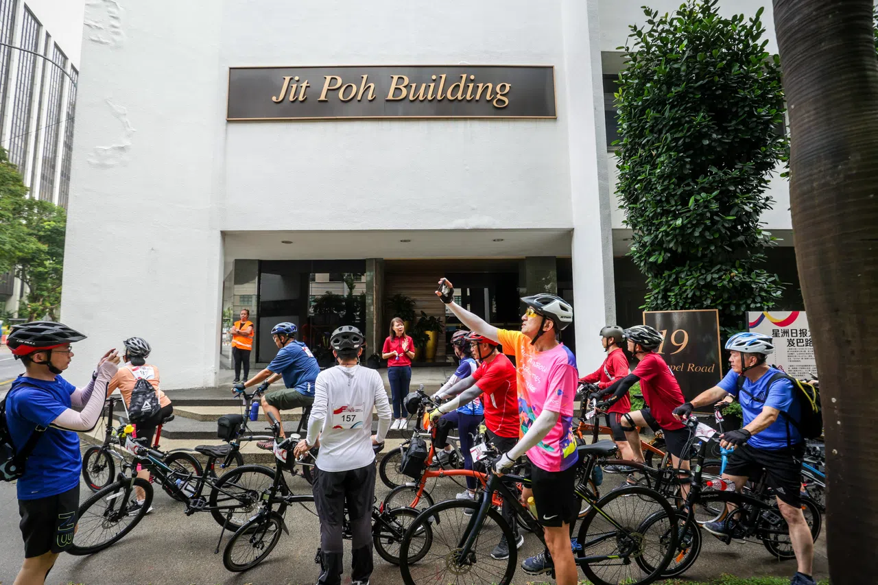《联合早报》副总编辑郭思满（中）为骑手们讲解《星洲日报》旧址日报大厦的历史。（叶振忠摄）