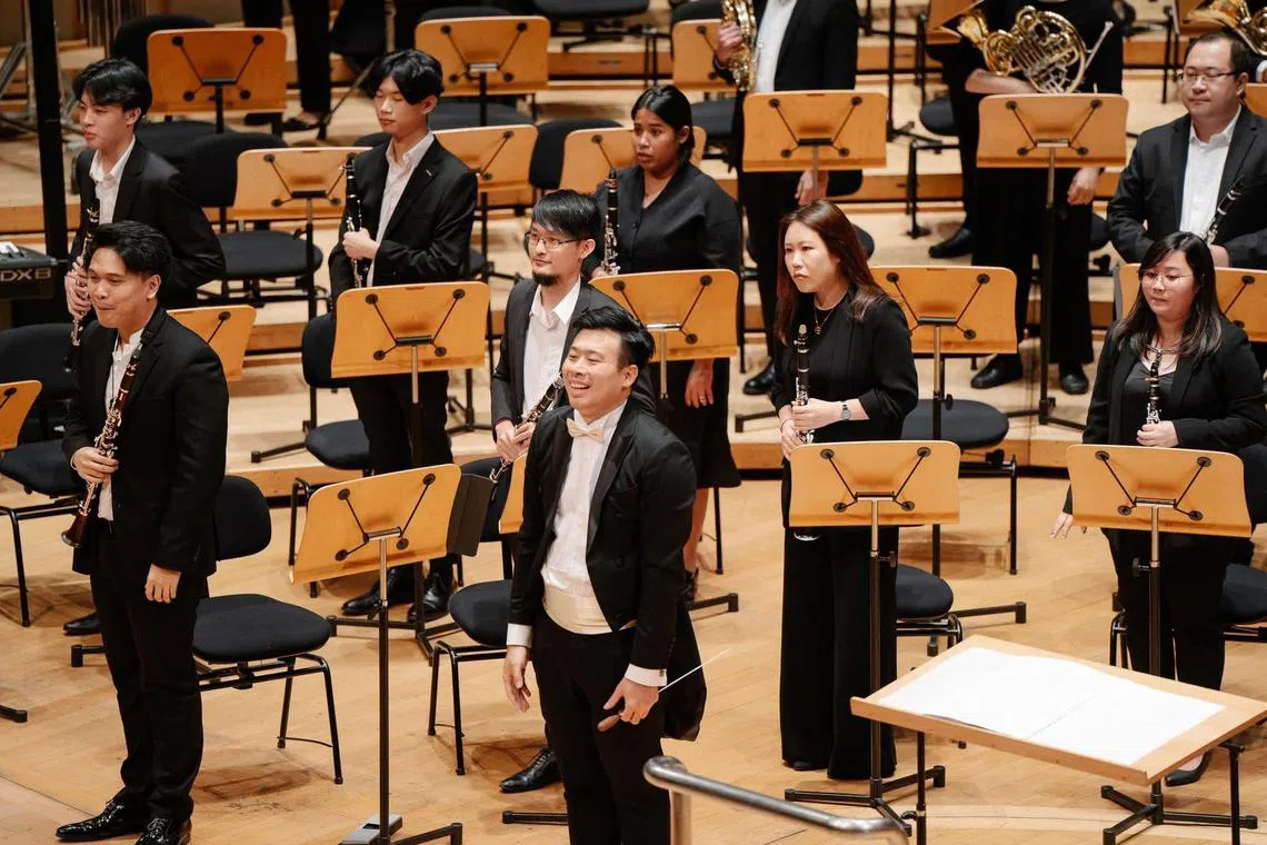 丹戎加东中学乐队指挥梁诒杰（中）是学校乐团计划的直接受益者。也是新加坡管乐指挥协会会长的他深信，乐团在传授音乐技巧之余，更能塑造学生的毅力和责任感。（受访者提供）