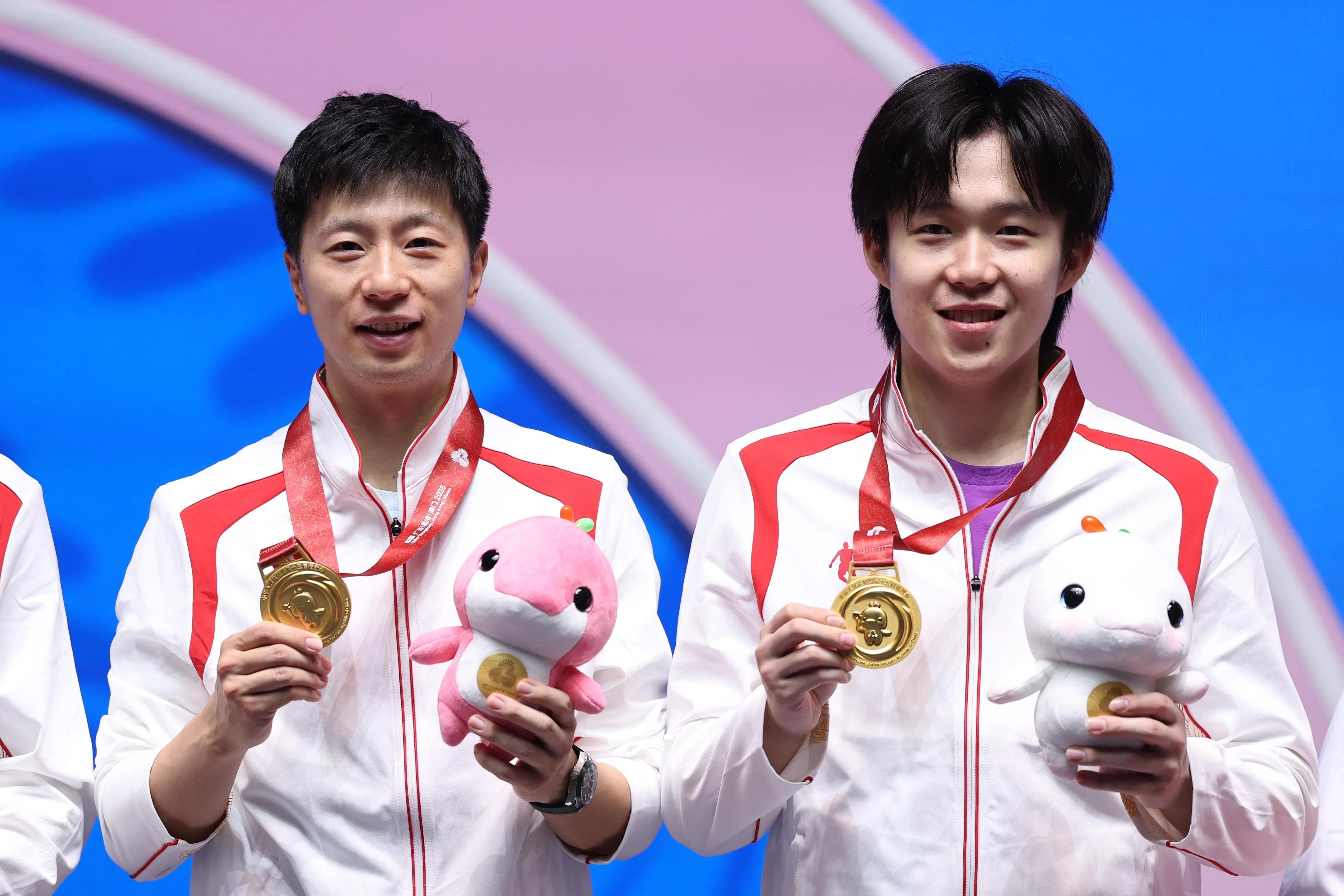 马龙（左）和王楚钦在颁奖台上展示金牌。（新华社）
