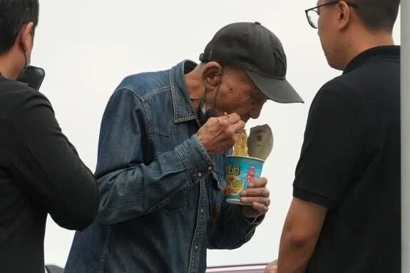 工作人员随即送上杯面，供李家鼎（中）充饥。（互联网）
