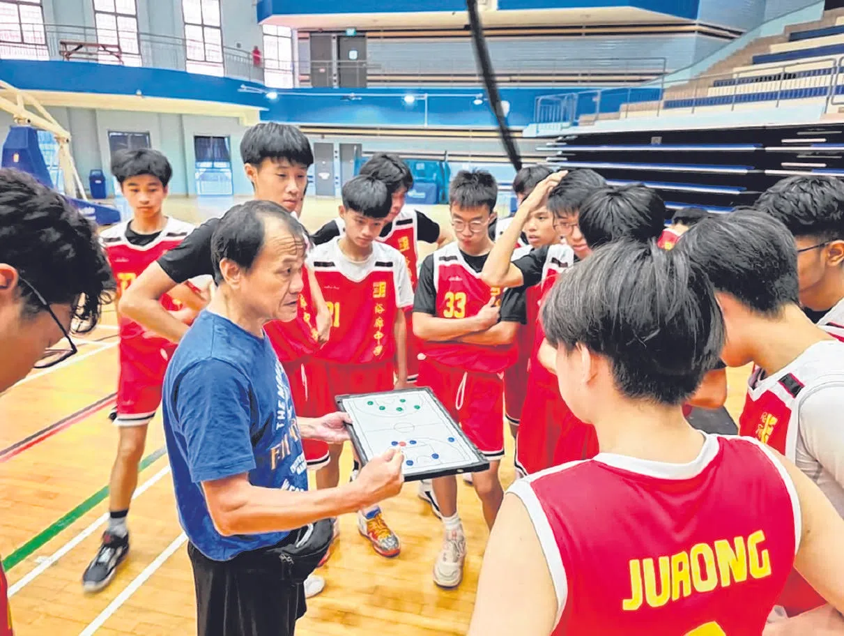 钟有生（蓝衣）生前曾指导裕廊中学篮球队44年。（新加坡篮球总会提供）