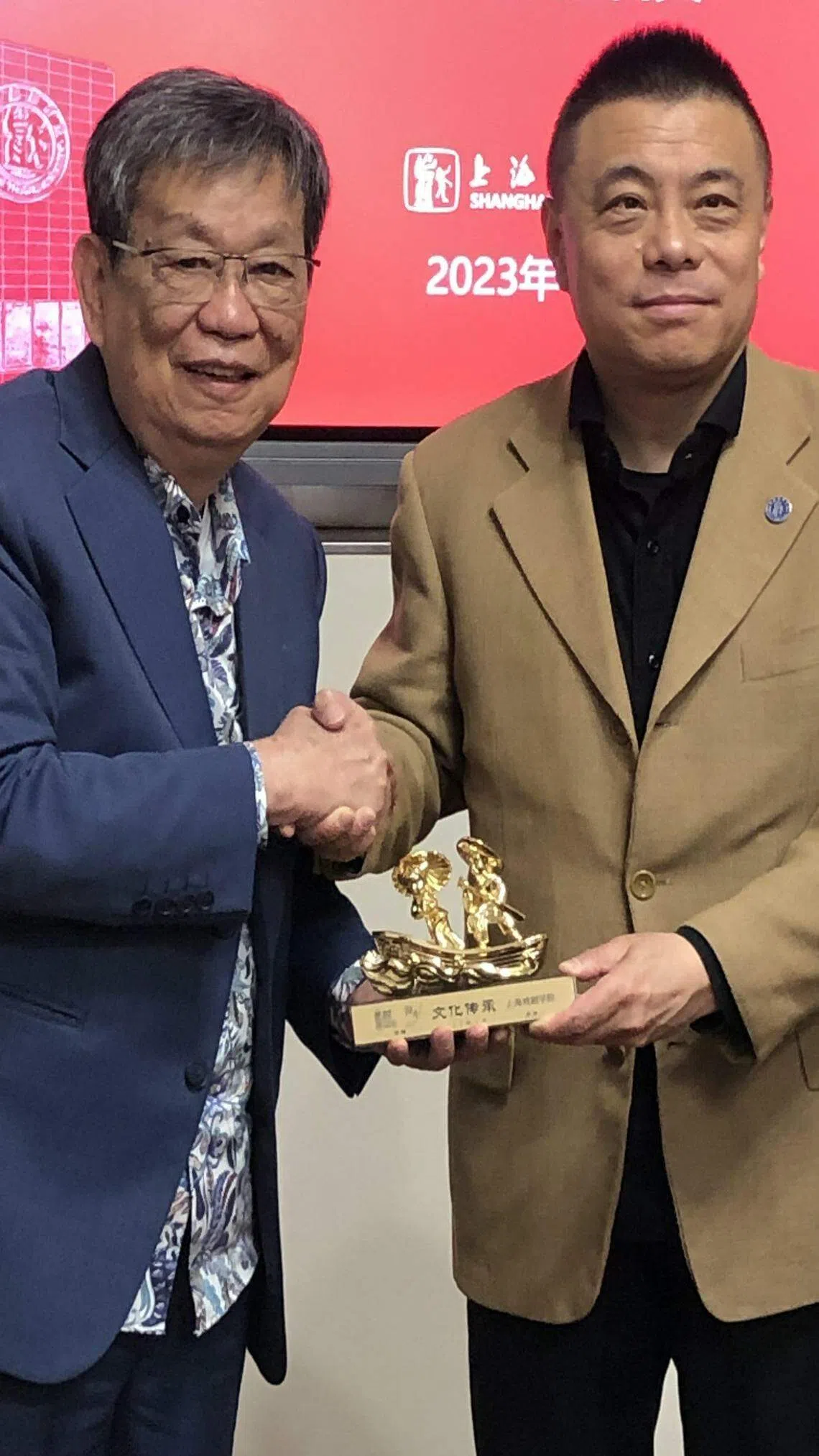 南华潮剧社社长卓林茂（左）赠送纪念品给上戏副院长张伟令。（谢燕燕摄）