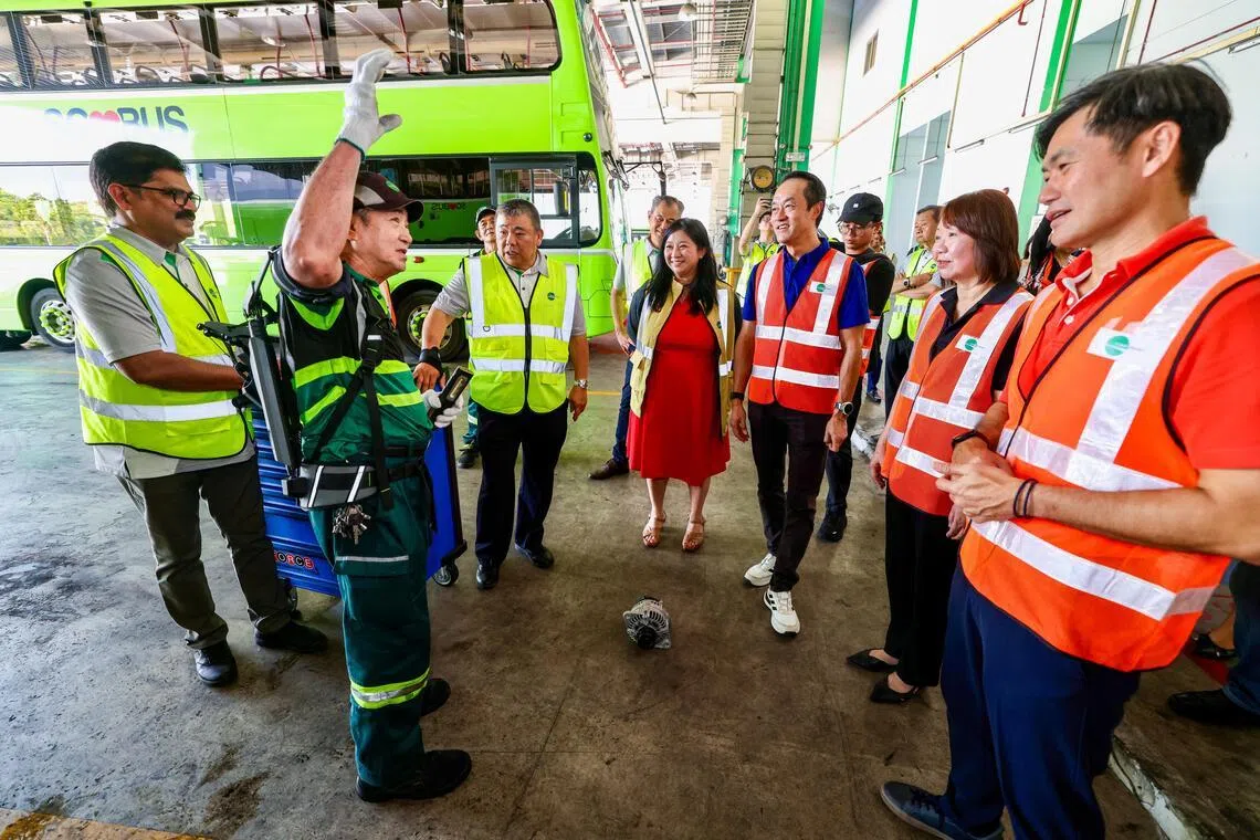 易塔通新加坡总裁卓文生（左三）介绍巴士技工使用的外骨骼装备，可减轻年长员工的体力负担。年长员工就业劳资政工作小组的几名领头人星期四走访易塔通武林巴士车厂了解情况。右起为全国职工总会副秘书长陈国明、新加坡全国雇主联合会副会长陈慧敏、人力部高级政务部长许宝琨医生、全国交通工友联合会执行秘书杨涴淩。（陈斌勤摄）