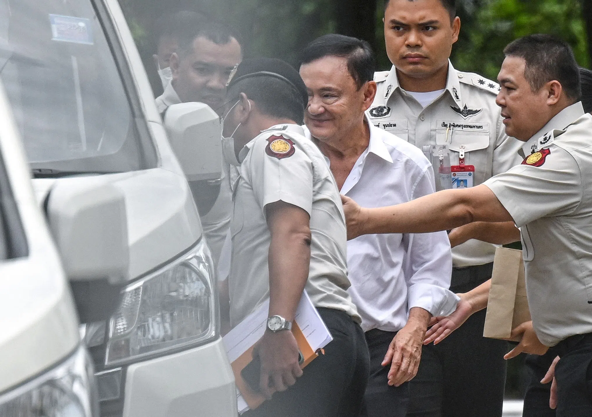 2025年9月9日，泰国前首相达信（中间白衣者）在曼谷最高法院外被押上警车。（法新社）