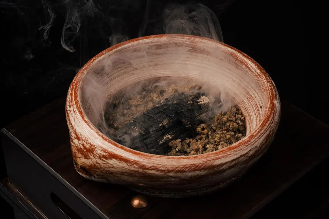 砂锅鸡饭上桌前加入烟熏橡木，让香味渗入米饭中。（餐馆提供）