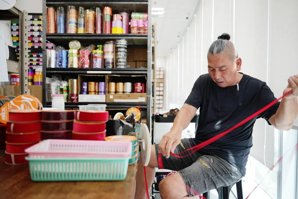 钦顺原以售卖丝带及向马来西亚和印度尼西亚出口商品为主，后创立自家品牌Minton Ribbons。图中员工正在卷丝带。（谢智扬摄）