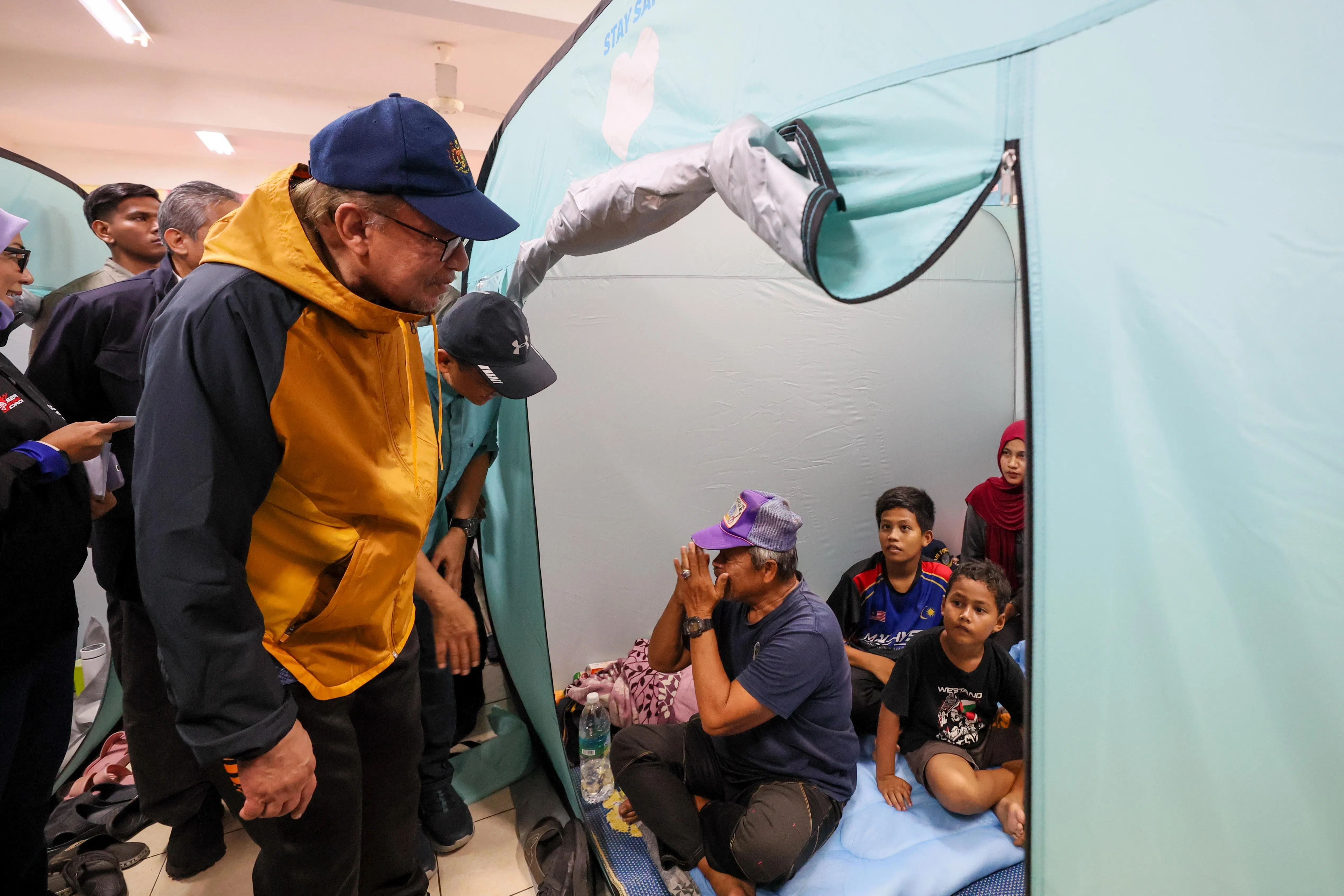 马国首相安华（左）星期天到登嘉楼甘榜特拉甲巴班的临时疏散中心探访水灾灾民。他宣布向吉兰丹和登嘉楼分别拨款额外2500万令吉（约753万新元），协助两州应对灾情和进行灾后管理工作。（马新社）