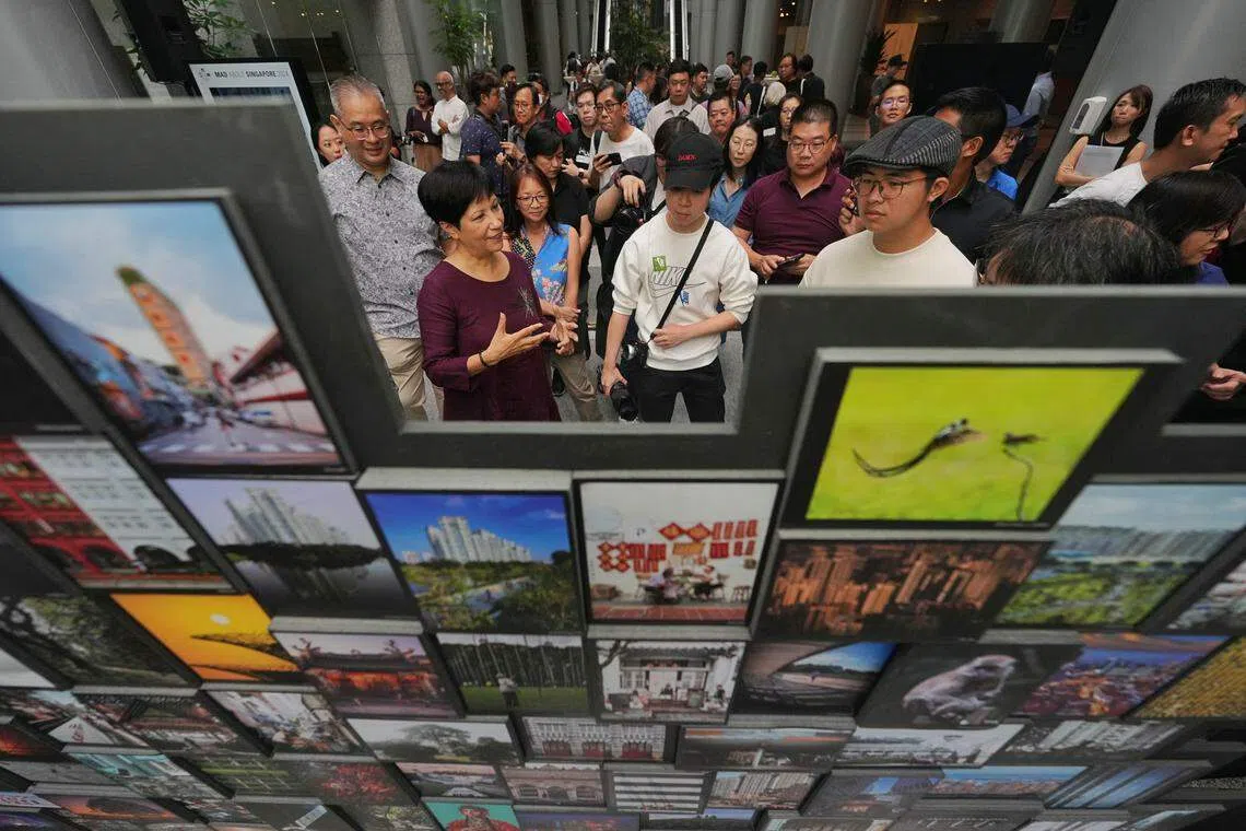 总理公署部长兼财政部及国家发展部第二部长英兰妮（前排左二）星期六为“为狮城疯狂”活动的摄影展主持开幕，并为在摄影比赛中分别获得第一名和第二名的莊竟（前排右起）和关骏雄颁奖。（谢智扬摄）