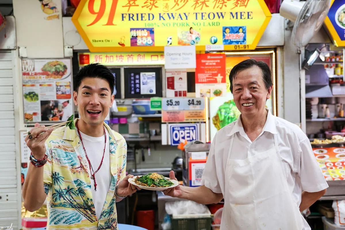 艺人杨志龙（左）喜欢翠绿炒粿条面摊主陈宏财在炒粿条加入青菜和江鱼仔的创意。（陈斌勤摄）