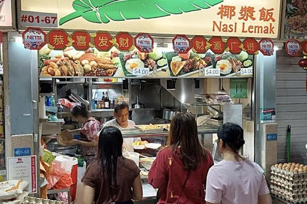 蔡万源（白衣者）过去40年来，都在黄埔熟食中心售卖椰浆饭。（取自网络）