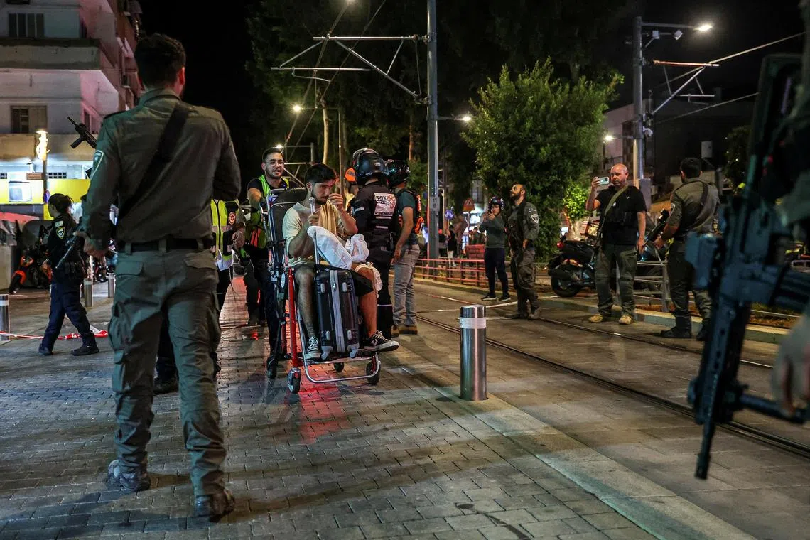 以色列中部城市特拉维夫南部雅法地区，星期二（10月1日）发生袭击事件后，救护人员把一名伤者带离现场。（路透社）