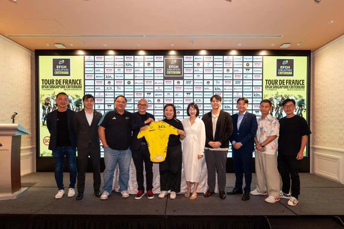 EFGH的创始人兼执行主席黄光锋（左四）和主办方Evoke Exp的总经理吴慧沁（左五）在活动上交换了签名协议，并手持知名车手波加查和温格高的签名黄衫合影留念。（环法新加坡绕圈赛提供）