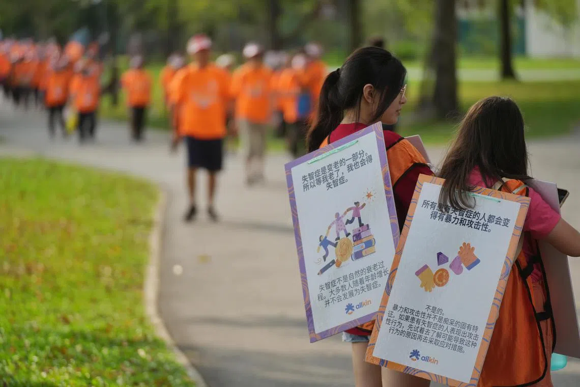 义工在沿途背上失智症科普硬纸板，站在现场引导秩序。纸板上以问答的形式写着关于失智症的知识点。（谢智扬摄）