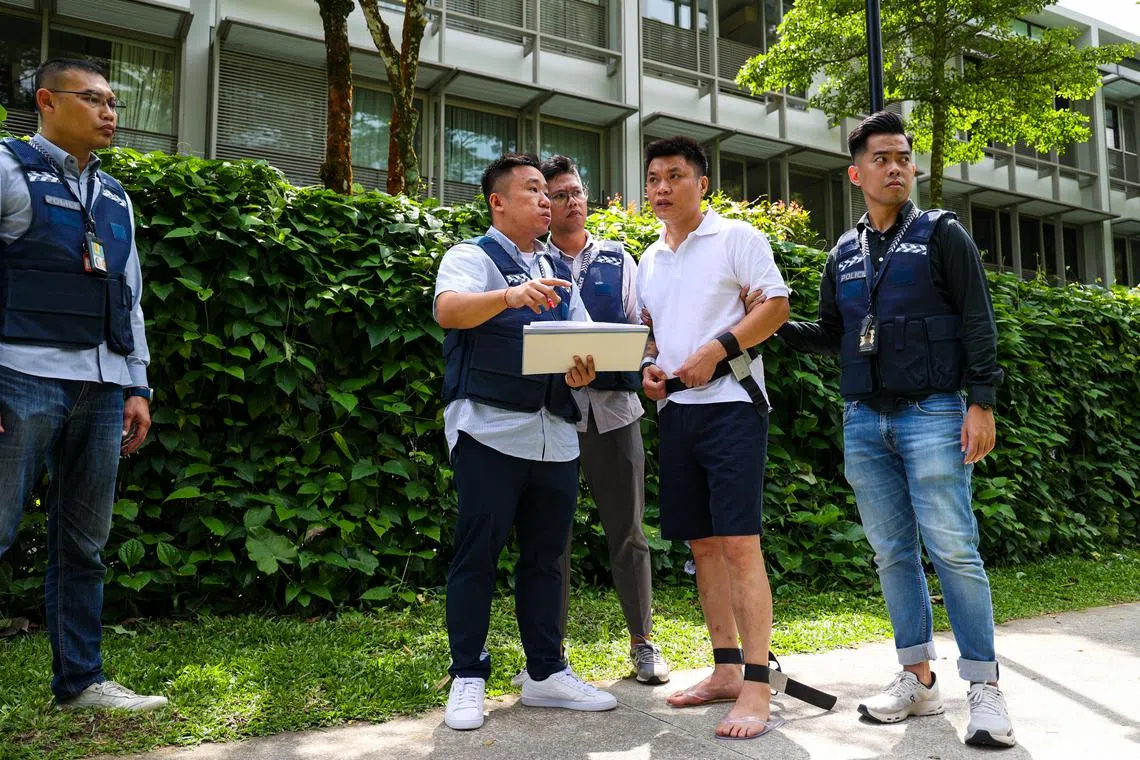 周英贵被押回现场时，表情严肃，走路时不断用眼睛打量着周围环境。（林明顺摄）