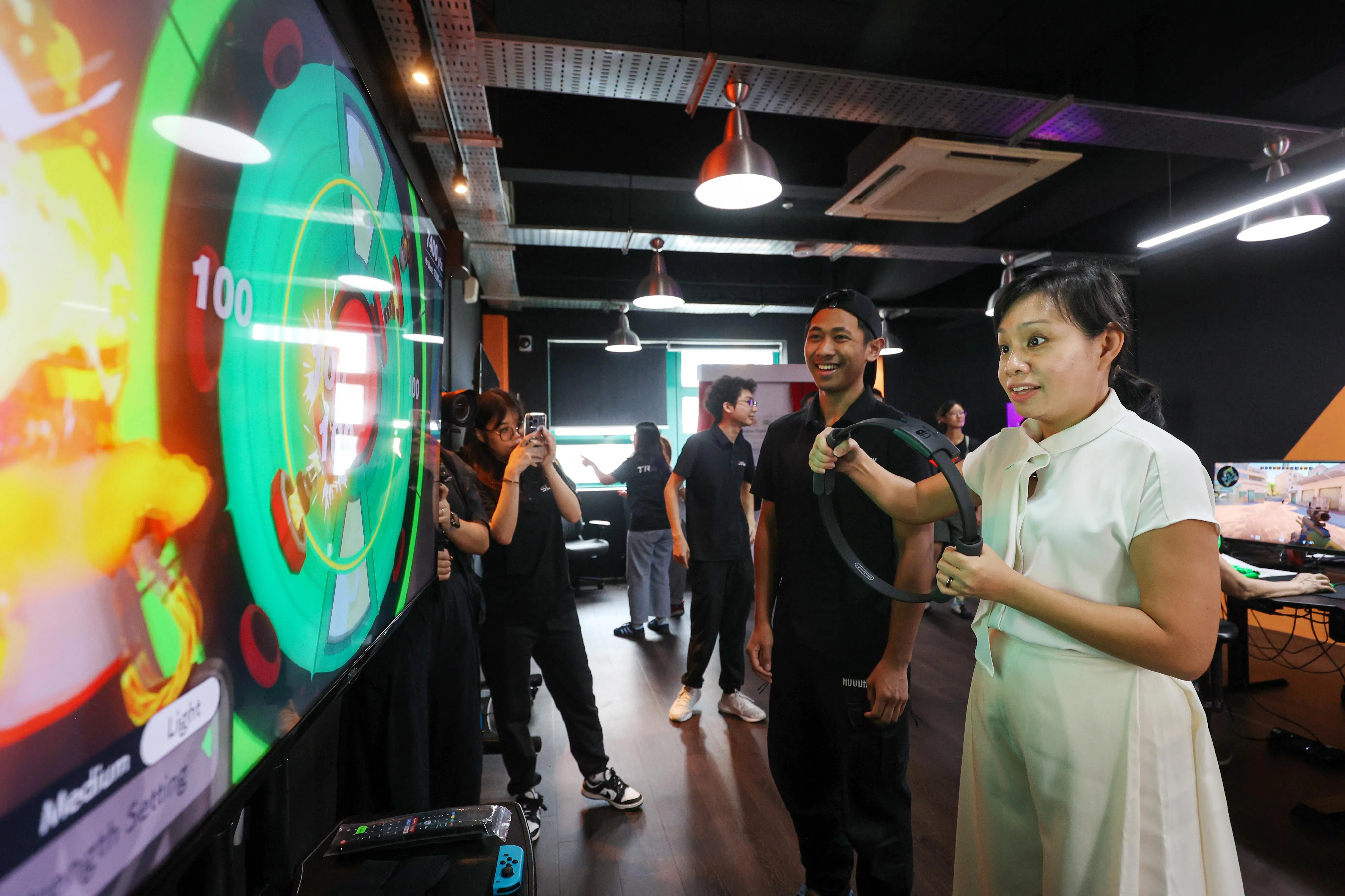 碧山—大巴窑集选区议员陈诗韵（白衣）星期天为电竞中心主持启用仪式，并在电子竞技学院专员指导下试玩体感游戏。（游甯稀摄）