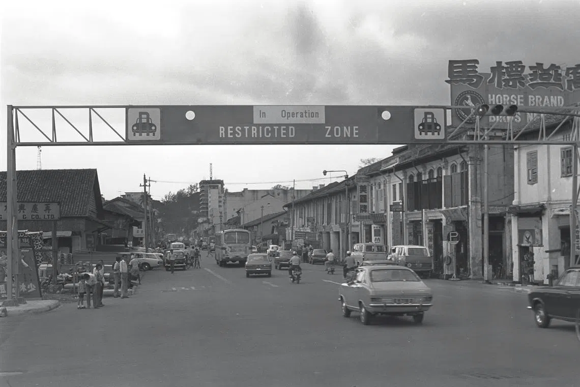 70年代的牛车水，路边都是矮店屋，“老爷车”在那时，是出行的幸福，抬头看到的，是第一代公路收费闸门。（档案照）
