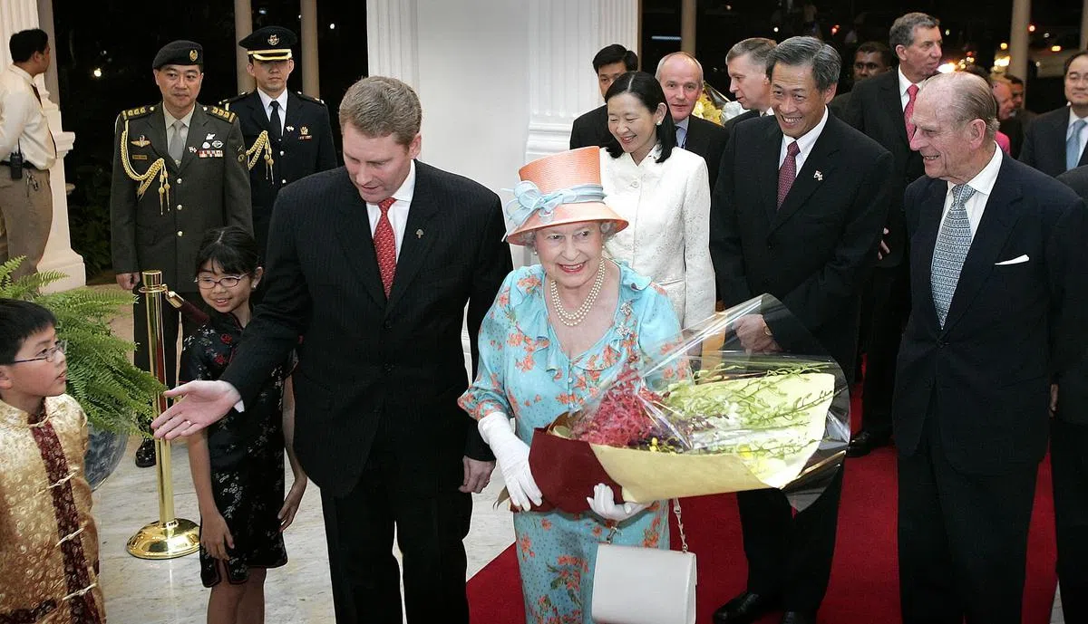 2006年3月16日,英女王伊丽莎白二世（中）在夫婿爱丁堡公爵（右一）陪同下，飞抵新加坡进行三天国事访问。两人在抵达下榻的莱佛士酒店时，受到酒店总经理罗伯特（结红领带者）热烈欢迎。时任人力部长的黄永宏（右二）是女王此行的陪同部长，在他身旁的是他的夫人。（档案照）