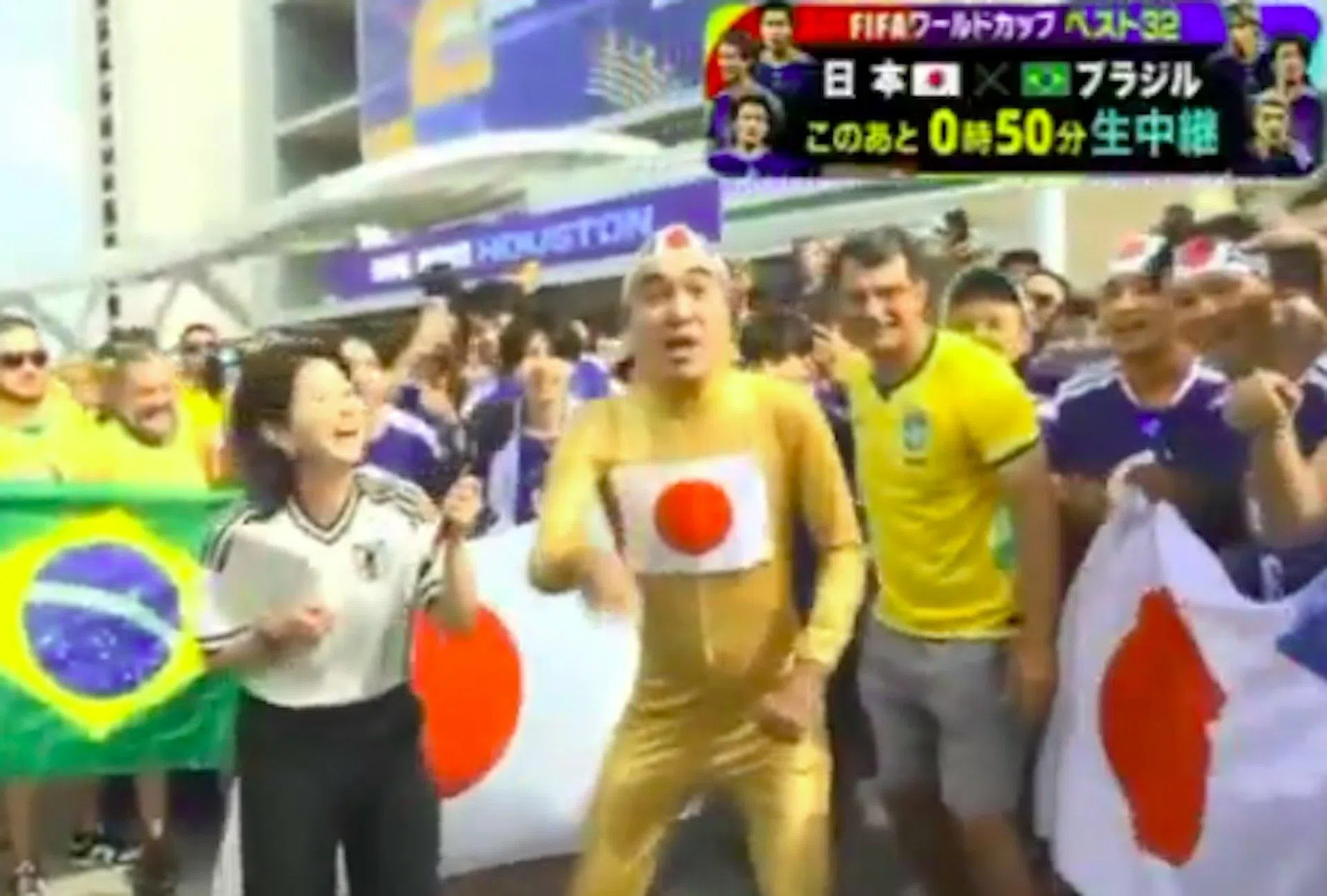 江头2:50（身前挂日本国旗者）和左边的主持人，在世界杯足球赛现场互动。（视频截图）