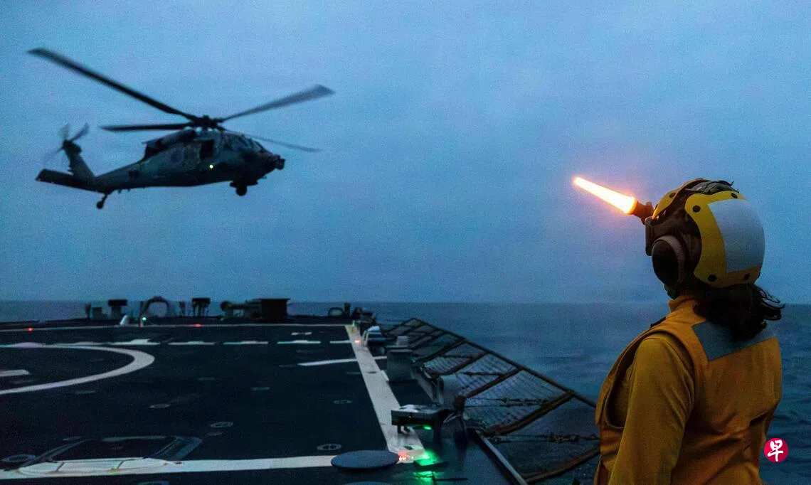美军导弹驱逐舰米利厄斯号（USS Milius）在波斯湾秘密海域执行“史诗怒火”行动。图为3月25日，一名美军在飞行甲板上引导一架“海鹰”直升机。 （路透社）