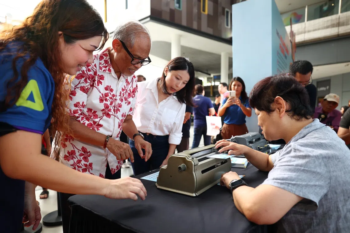 林丽丽（右）在“志愿者嘉年华”当义工，向公众示范如何使用盲文打字机。（林明顺摄）