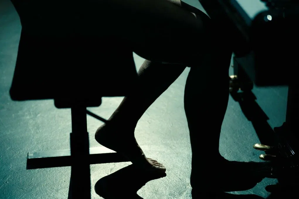 在舞台上弹琴的王西麟。在光影之间，黑暗遮盖身体，他就是那个黑衣人。（影片截图，Goodman Gallery图片）