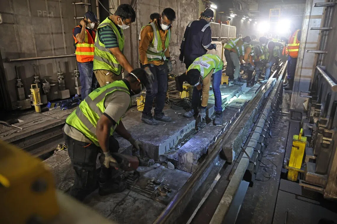 旧铁轨从隧道基座中取出后，工程人员必须把底层残留的旧橡胶逐一铲除，确保新嵌入式轨道能稳固就位。（陈渊庄摄）