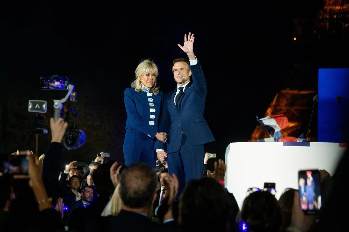 法国总统马克龙（右）昨天在第二轮总统选举的出口民调结果出炉后，在首都巴黎与妻子布丽吉特向支持者致谢。（彭博社）
