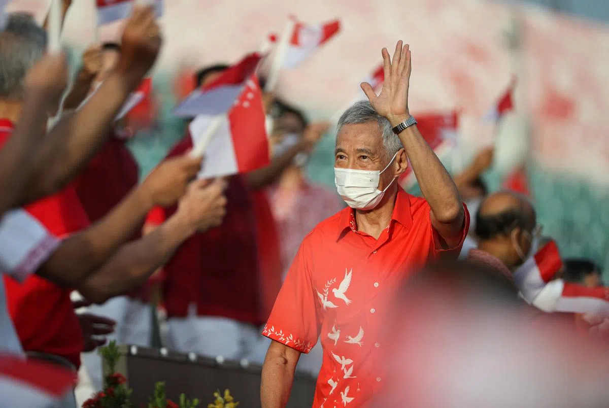   李显龙总理抵达会场时向受邀出席者挥手致意，他们当中包括医护人员和安全距离大使等在不同岗位上做出贡献的前线人员。（李健玮摄）