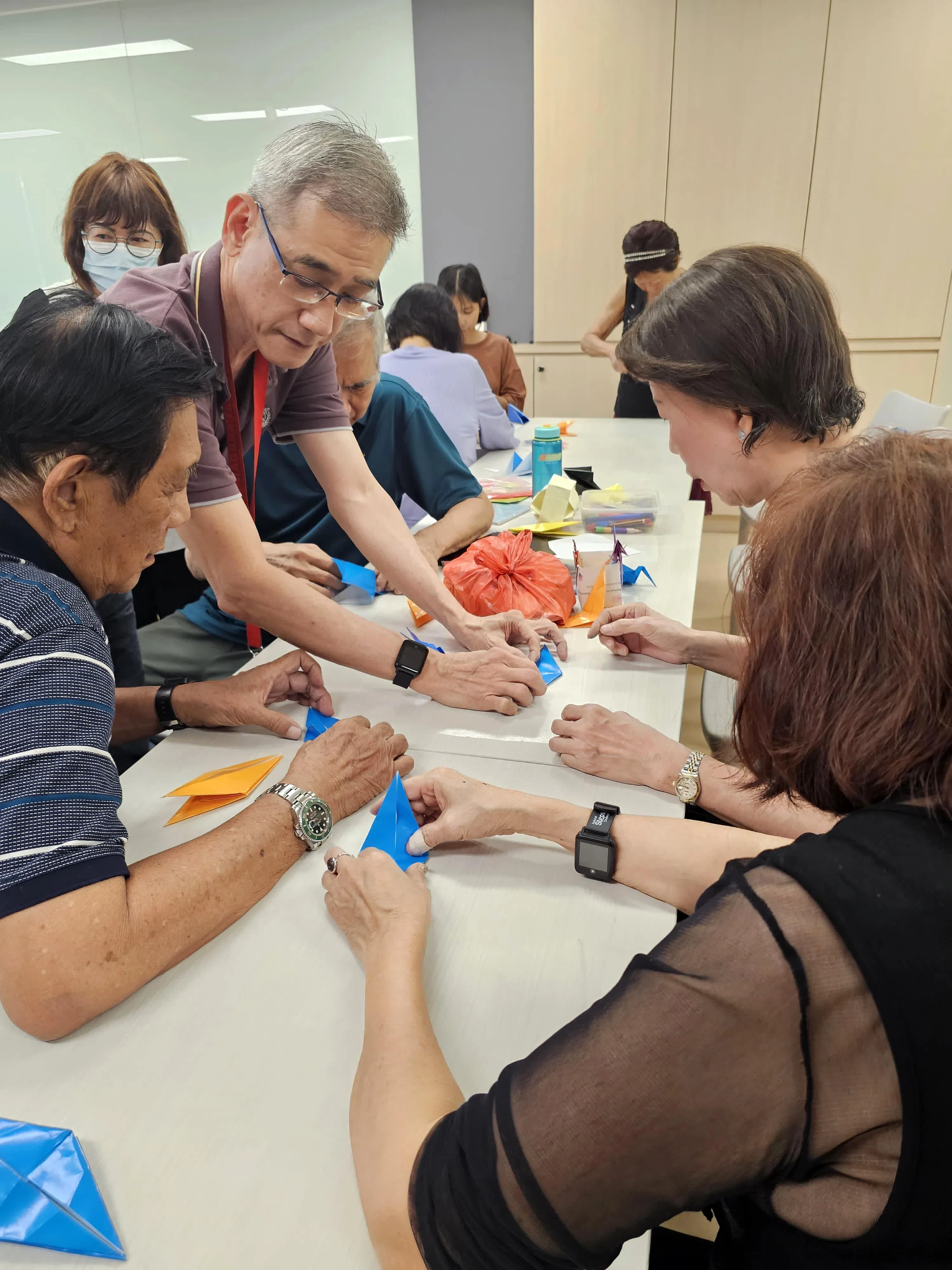 加基武吉民众俱乐部社区义工吴开烈（左二）12月31日指导18名居民和义工折纸鹤。倒数活动当天，他们还会动员更多阿裕尼集选区及后港区居民，合力完成2025只千纸鹤，共同为国家献上祝福。（加基武吉选区办事处提供）